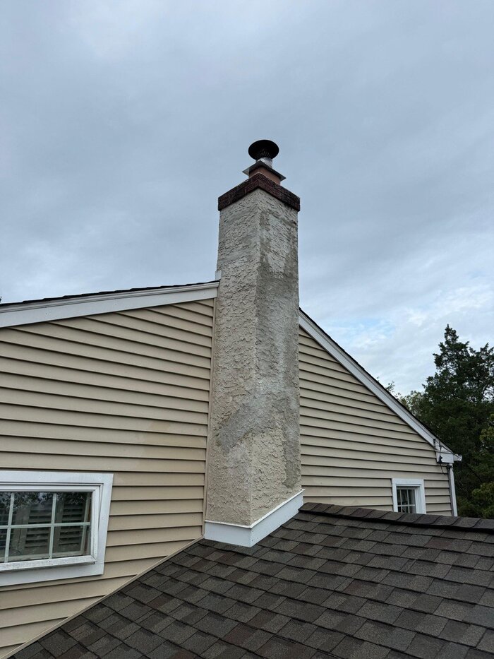 Full height stucco chimney with cap on residential home
