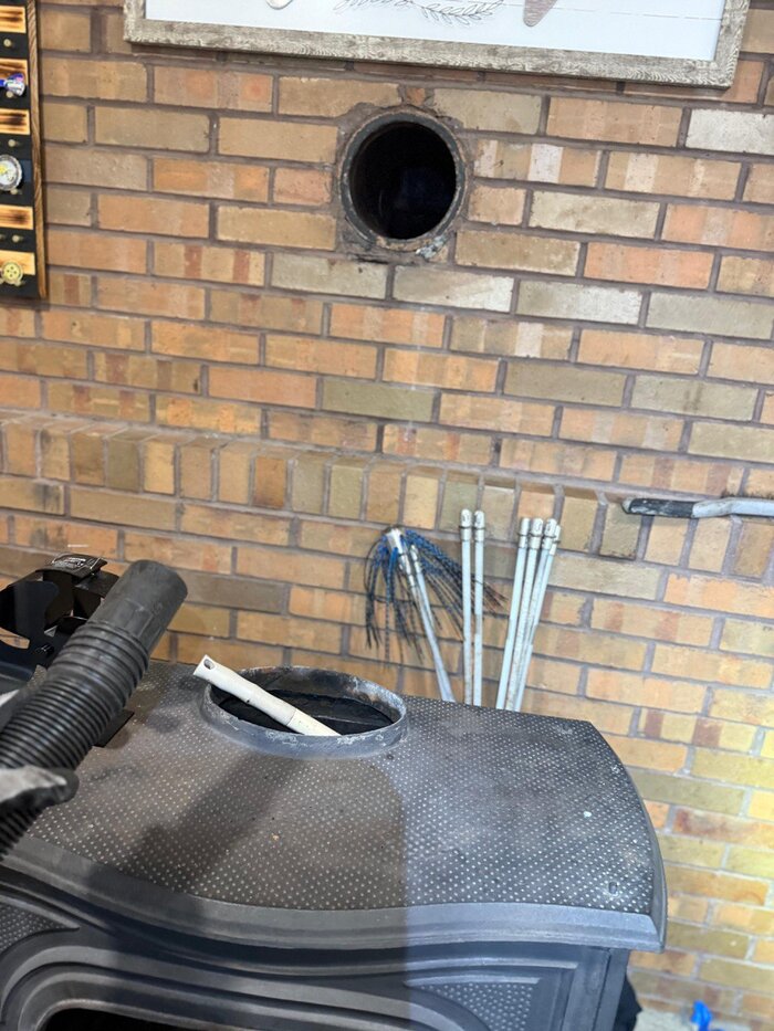 Professional chimney sweep in progress with rotary brush and vacuum