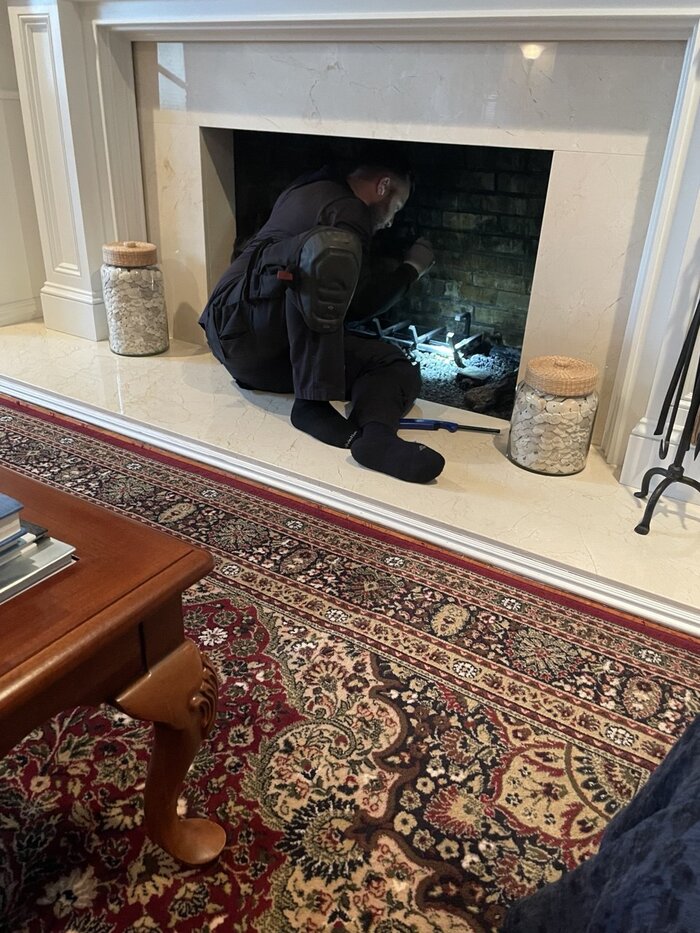 Chimney technician inspecting firebox interior in Northern NJ home