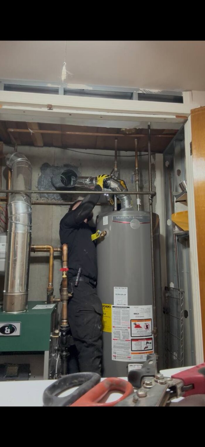 Technician working on flue pipe connection in utility room